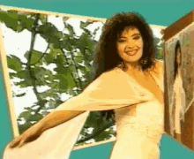 a woman in a white dress is smiling in front of a picture frame