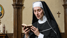 a nun is reading a book in a church