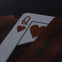 a queen of hearts playing card is laying on a table