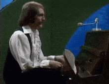 a man in a white shirt is sitting at a piano and clapping his hands