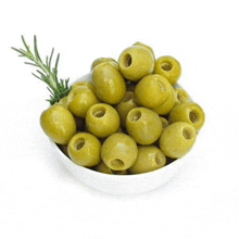 a white bowl filled with green olives with holes in them