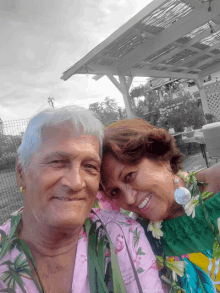 a man and a woman are posing for a picture and the man is wearing a pink shirt with flamingos on it