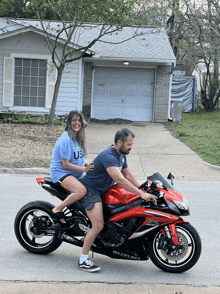 a man is riding a red suzuki motorcycle with a woman sitting on the back