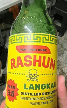 a person is holding a bottle of rashun langkau distilled rice liquor