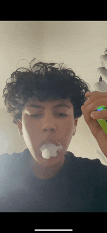 a young man with curly hair is smoking a cigarette with smoke coming out of his mouth