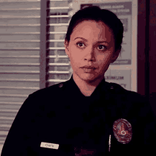 a woman in a police uniform is standing in front of a window in a police station .