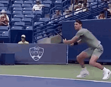 a man is swinging a tennis racket on a tennis court in front of a banner that says us open