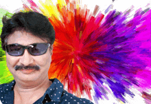 a man wearing sunglasses stands in front of a colorful explosion