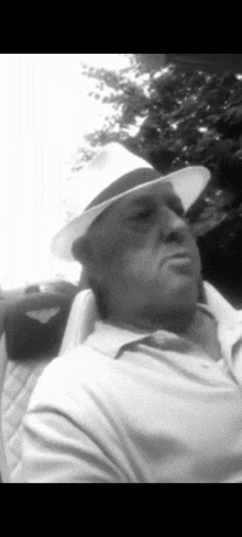 a man wearing a white hat and a white shirt is sitting in a chair .