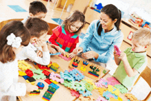 a group of children are playing with puzzles and a woman is smiling at them