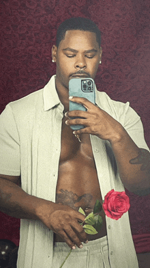 a shirtless man is taking a selfie with a rose