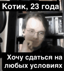 a man with glasses is sitting in front of a bookshelf with the words kotik 23 года