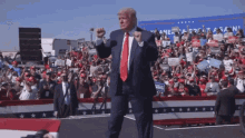 a man in a suit and tie stands in front of a crowd with a sign that says " america great again "