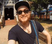 a man wearing sunglasses and a hat stands in front of a building that says ' temple ' on the front