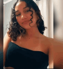 a woman with curly hair takes a selfie in a black top