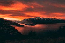 a lake with mountains in the background and a red sky