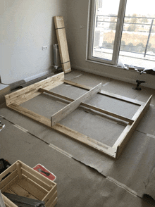 a wooden bed frame is being built in a room next to a window