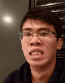 a young man wearing glasses is making a funny face with his mouth open