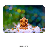 a statue of ganesha is surrounded by white flowers and has the word kulfy on the bottom