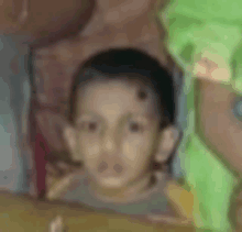 a little boy with a green shirt on is sitting on a table .