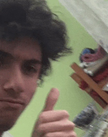 a man with curly hair is giving a thumbs up sign in a blurry photo .