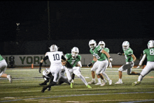 a group of football players on a field with a sign in the background that says new york