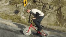 a man is riding a bike down a hill next to a yellow sign that says ' a ' on it