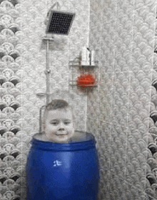 a young boy is sitting inside of a blue barrel in a bathroom .