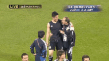 a man in a black tank top stands on a soccer field with two other men and a sign that says live