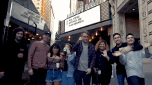 a group of people are posing for a picture in front of a sign that says ' night hall '