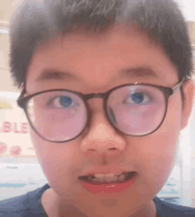 a young boy wearing glasses is making a face .