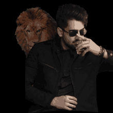 a man wearing sunglasses holds a glass of whiskey with a lion in the background