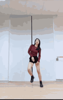 a woman in a red top and black shorts is dancing