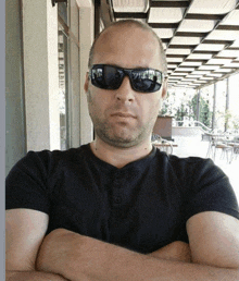 a bald man wearing sunglasses and a black shirt