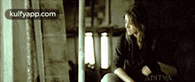 a woman is sitting in front of a window in a dark room .