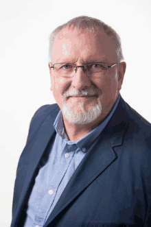 a man wearing glasses and a blue jacket is smiling