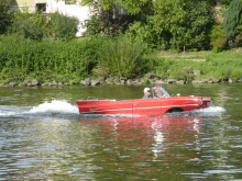 a man is driving a red boat in the water