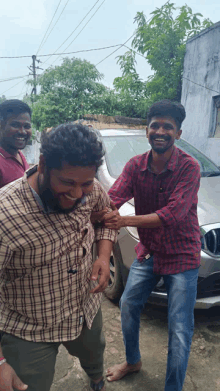 a man in a plaid shirt is being helped by another man in a red shirt