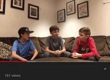 three young boys are sitting on a couch and one of them is wearing an all nut shirt