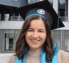 a woman wearing a graduation cap and gown is smiling and standing in front of a building .