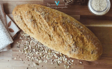 a loaf of bread sits on a wooden cutting board next to a jar of grain