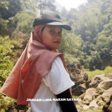 a girl wearing a hijab and a hat with the words jangan lupa makan sayang written on the bottom