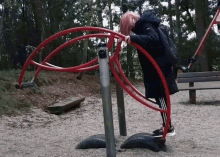 a girl with pink hair is playing on a playground with a red object that says ' adidas ' on it