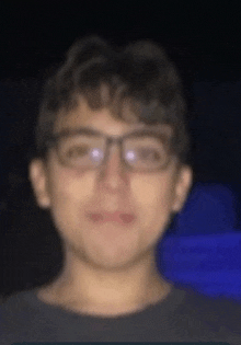 a blurry picture of a young boy wearing glasses and a black shirt .