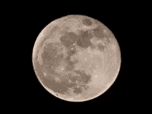 a full moon against a black background with a few clouds