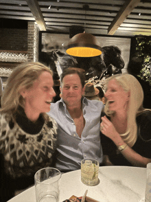 a man and two women are sitting at a table with a drink on the table