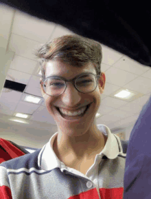 a young man with glasses and a striped shirt smiles for the camera