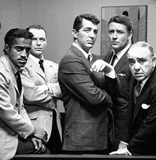 a group of men in suits and ties standing next to each other .