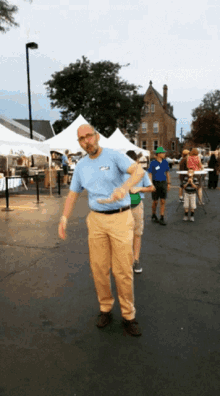 a man in a blue shirt with a name tag that says ' a ' on it is standing in a parking lot