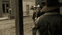 a man in a cowboy hat stands in front of a building with a sign that says ' saddle ' on it